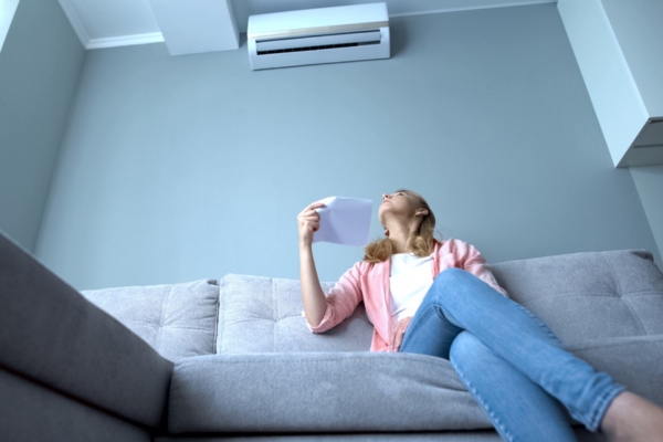 woman feeling warm looking at AC unit depicting importance of AC compressor