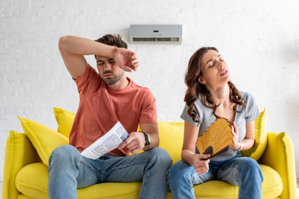 couple feeling warm in front of broken air conditioner