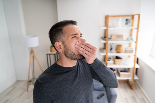 man covering his nose due to bad smell coming from air conditioner depicting mold growth