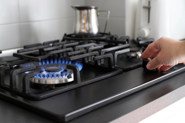 homeowner turning on propane powered stove depicting maintaining desired cooking temperature