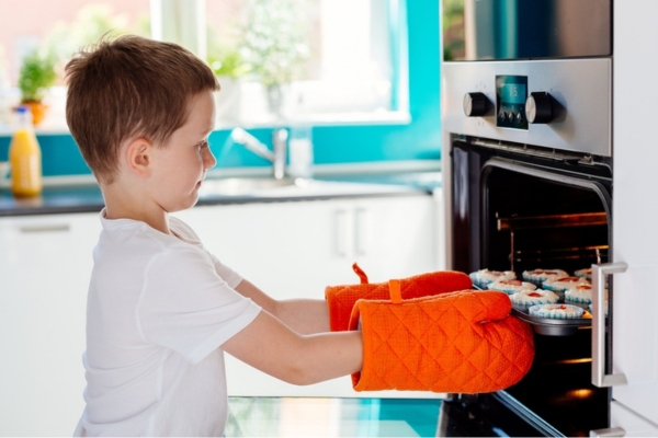 young boy putting cupcakes inside propane powered oven