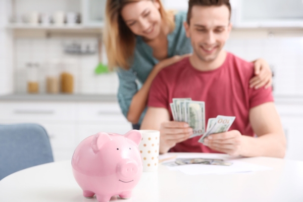 couple counting money behind a focused piggy bank depicting energy savings