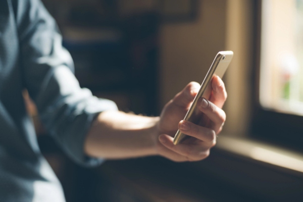 image of a person's hand using a mobile phone depicting connecting smart oil gauge to Alexa