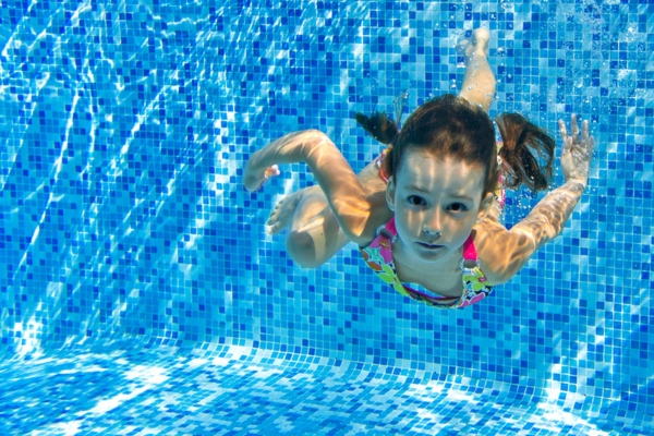 child swims underwater in a heated pool