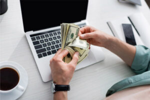 man at computer with money depicting heating oil fuel prices